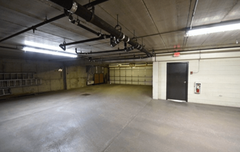 A large, empty warehouse with a concrete floor and a fire extinguisher on the wall.